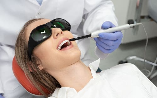female patient undergoing laser dental treatment in modern dental chair